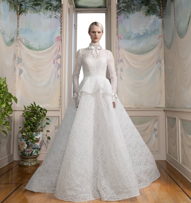 An all-lace peplum long sleeve gown with a satin bow at the collar. 