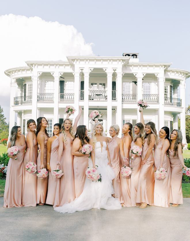 The bride and her bridesmaids stand outsider her wedding venue in Houston.