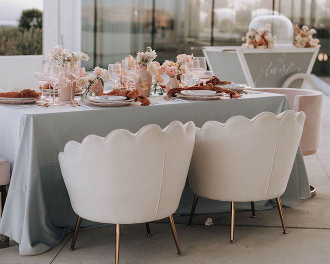 A table with a sage green tablecloth and peach toned table decor on the covered rooftop of POST Houston. 