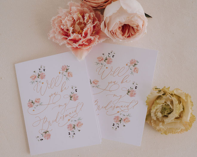 Two cards reading "Will you be my Bridesmaid?" with a floral print around it. 