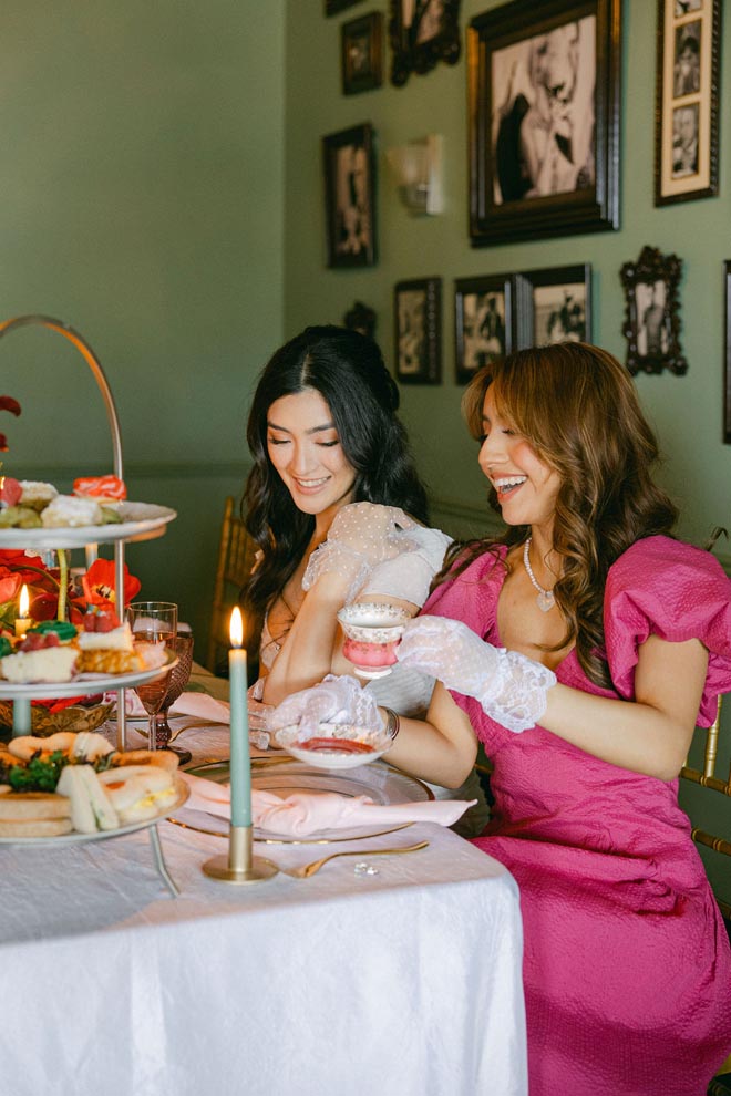 The bride and her bridesmaids laugh while drinking tea at the bridal shower.