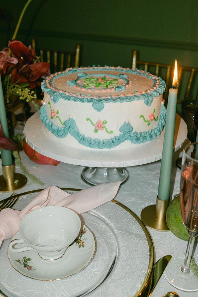 A pink and blue cake is placed on a white cake stand.
