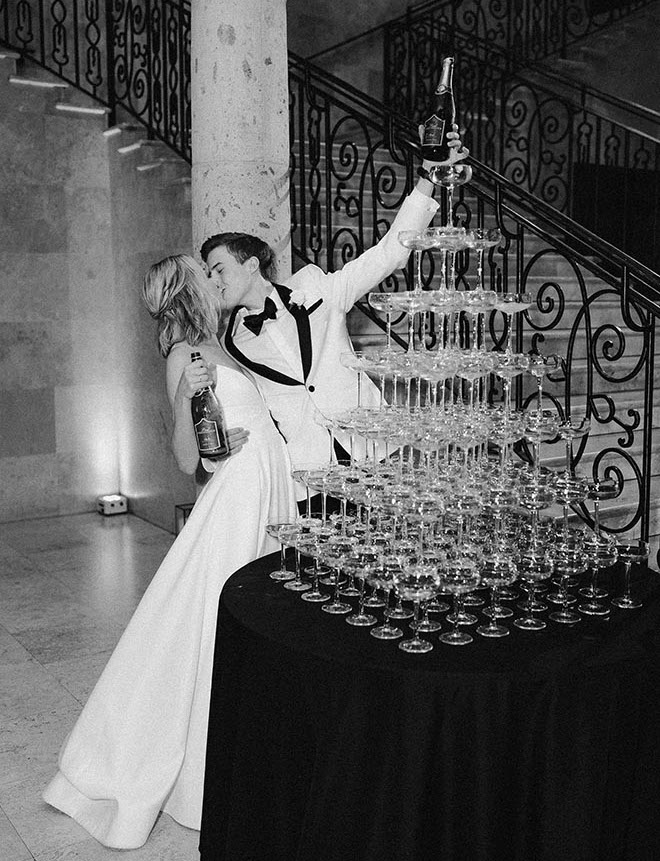 The bride and groom kissing white pouring champagne into a champagne tower. 