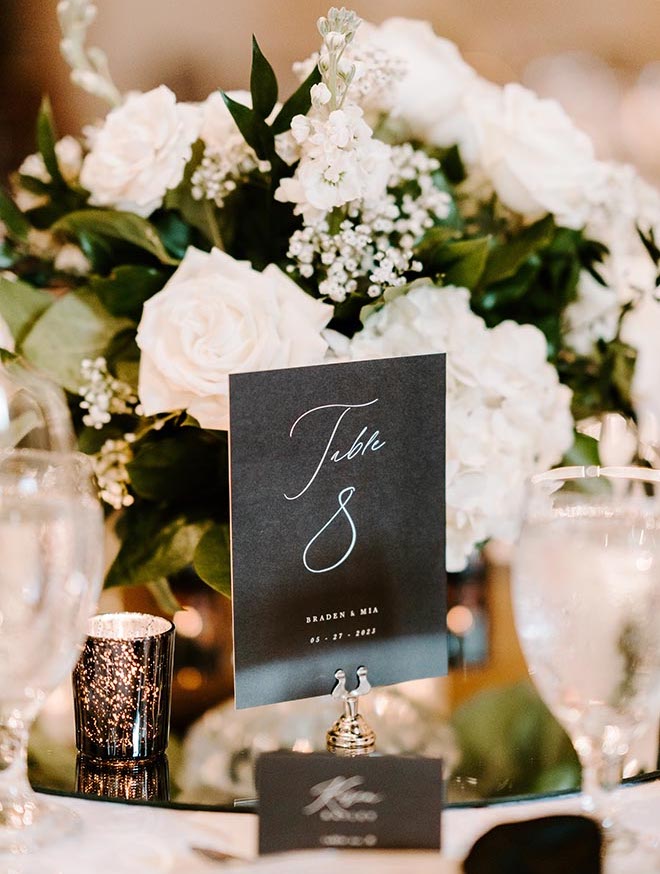 A black and white table number and a white floral centerpiece. 