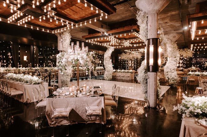 The Houston wedding venue, The Astorian, is decorated in white florals for the Broadway-styled reception.