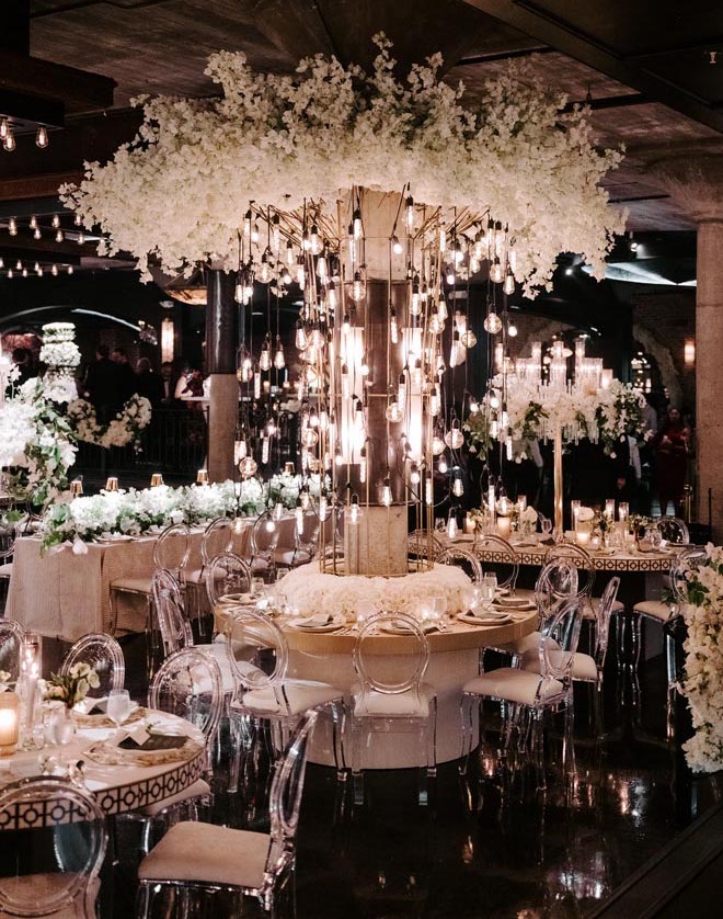 White floral instillations, candlelight and dangling light bulbs decorate The Astorian's reception space.