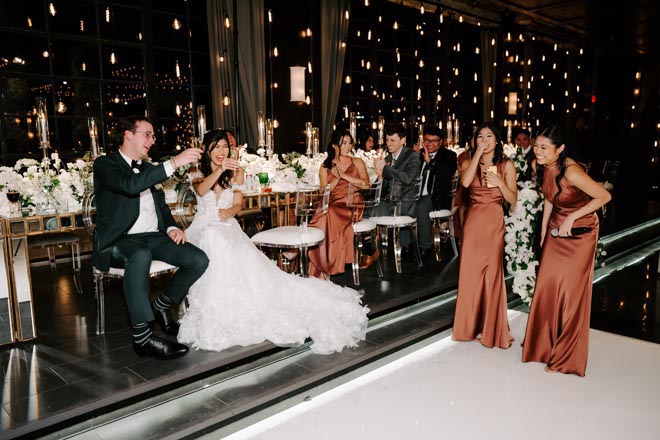 The bride and groom raise their glasses at their Broadway-styled reception at The Astorian.