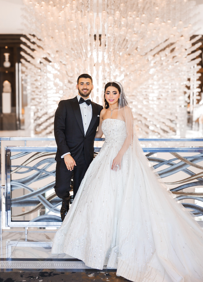 Bride and groom smiling in front of the grand chandelier at The Post Oak Hotel at Uptown Houston. 