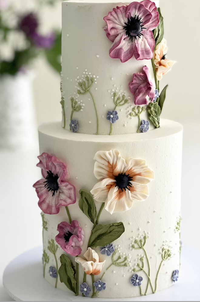 A three-tiered cake is designed in hand painted and fondant flowers. 