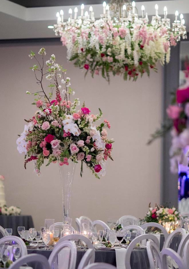 Pink floral centerpieces and hanging floral instillations decorate the ballroom wedding reception at the Omni Houston Hotel. 