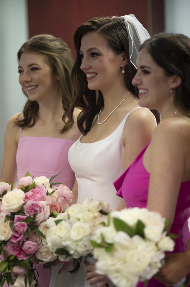 The bride and her bridesmaids smile while holding their wedding bouquets. 