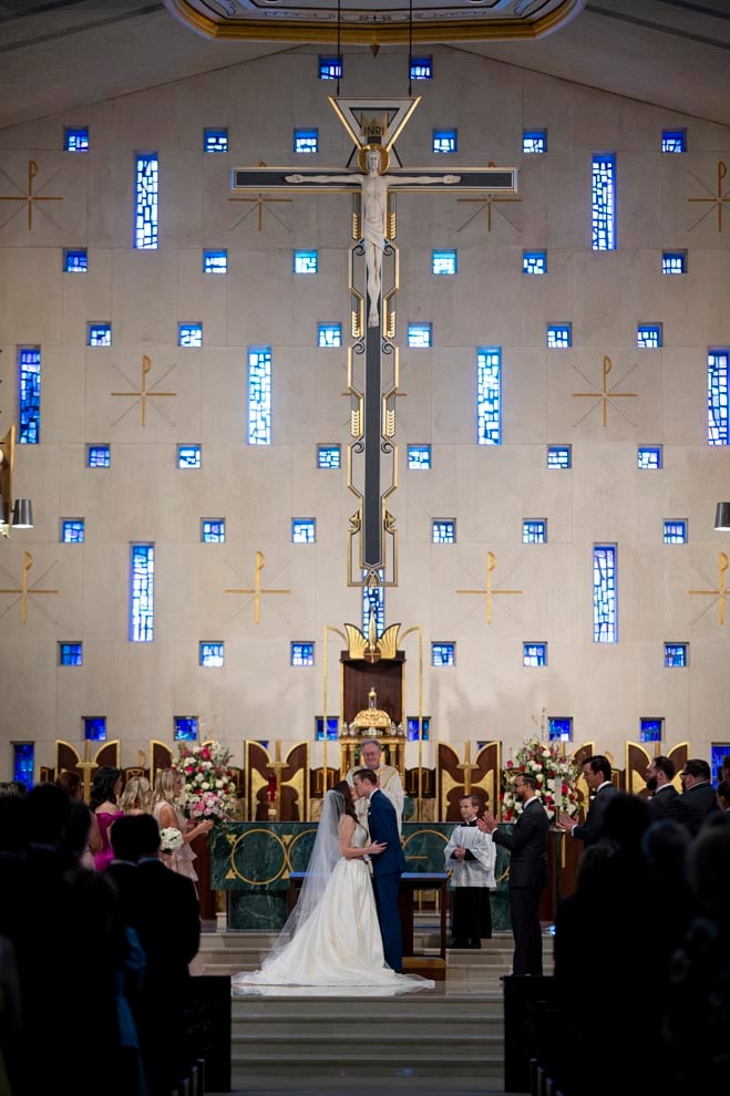 The bride and groom share a kiss on the altar at their church ceremony. 