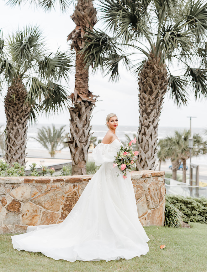 The bride stands along the Texas Gulf Coast holding her wedding bouquet. 