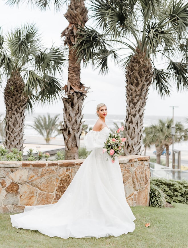 The bride stands along the Texas Gulf Coast holding her wedding bouquet.
