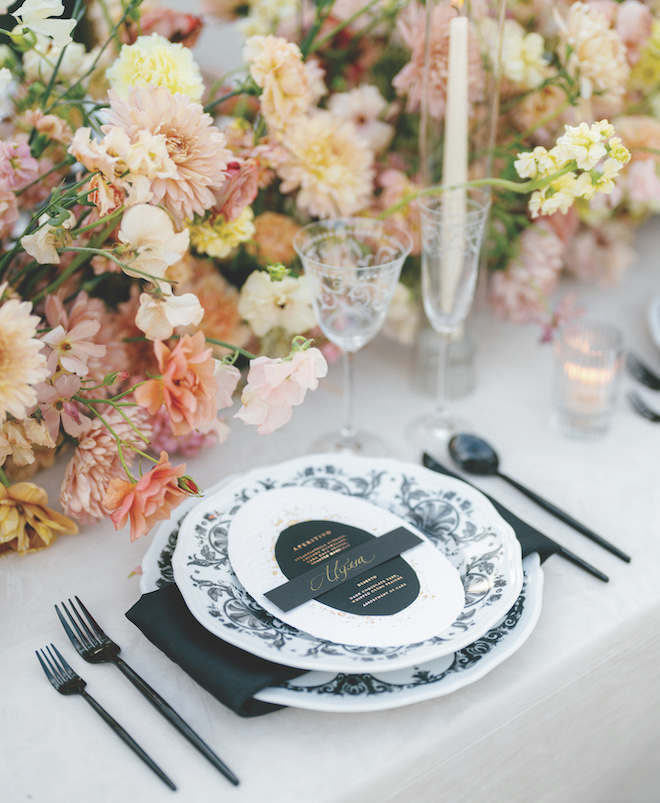 Black and white plates, stationery and flatware with peach-hued florals as the centerpiece. 