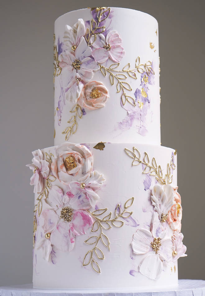 A two-tiered cake is detailed in pink and purple flowers. 