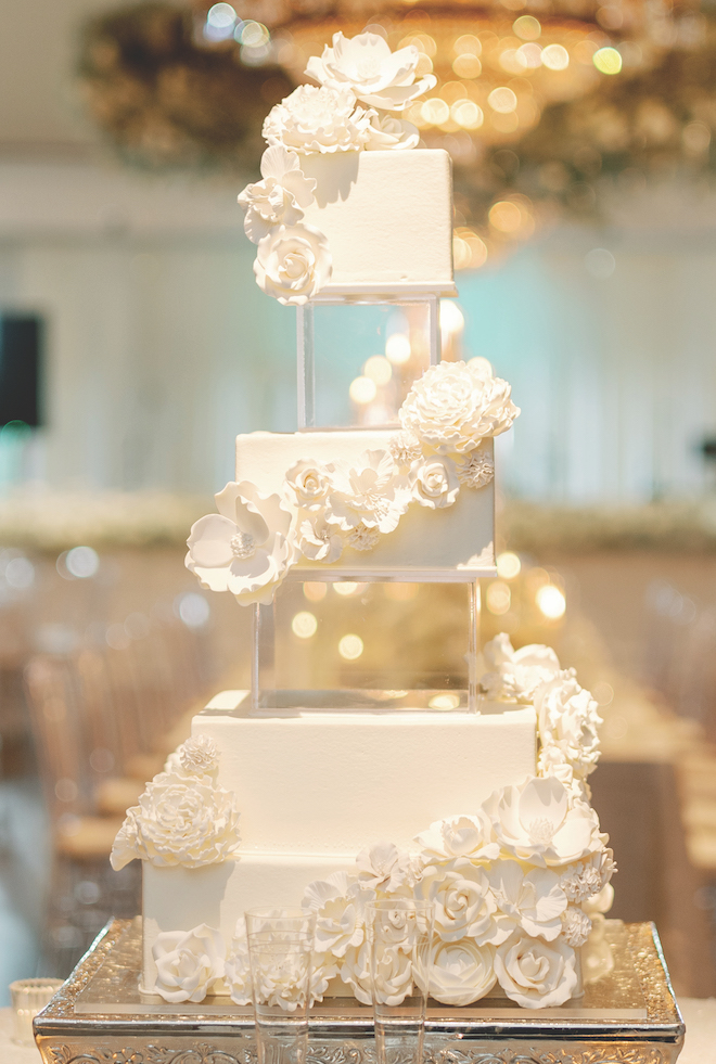 Susie's Cakes designs an elegant wedding cake with acrylic tiers and white fondant roses. 