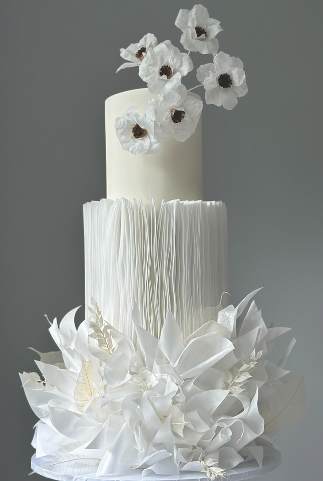 A white, three tiered elegant wedding cake designed by Sweet Homemade. 