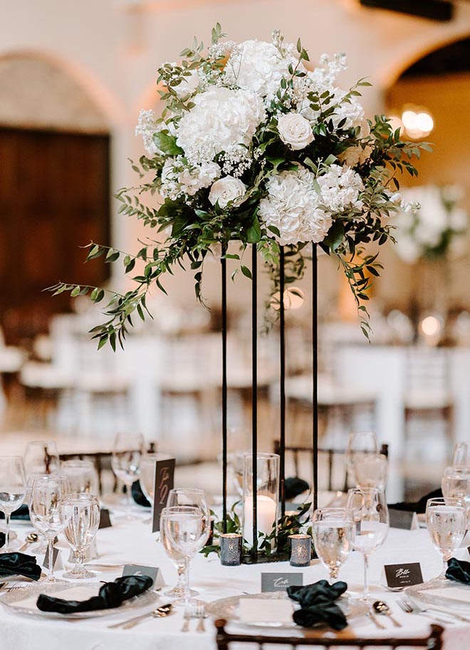 Tall floral centerpieces with greenery and white florals on the reception tables. 