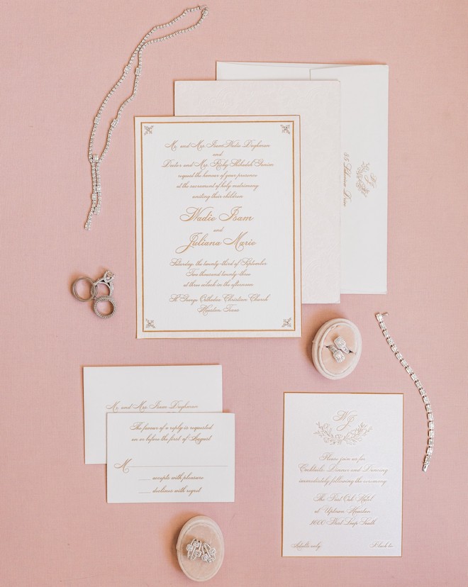 White and gold wedding invitations against a pink background from Bering's.