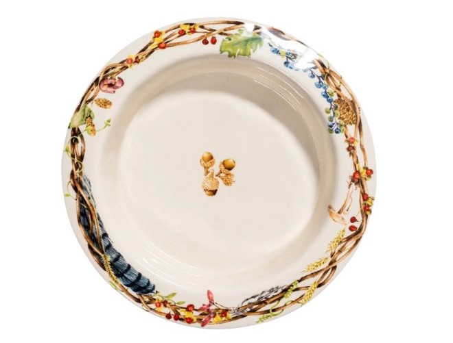 A plate with fall foliage on the rim of the plate with acorns in the center.