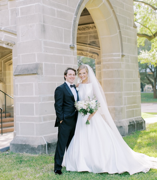 The bride and groom smiling outside of the church.
