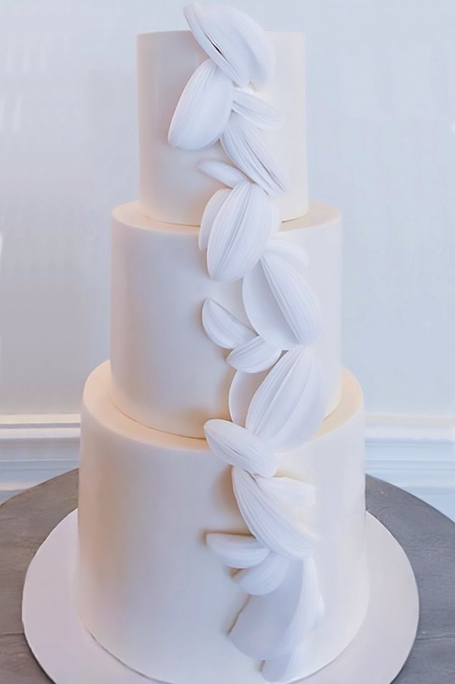 A three tier white wedding cake with unique embellishments by Alchemy Bake Lab.