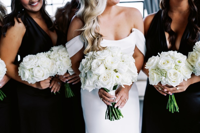 The bride and bridesmaids holding white floral bouquets.
