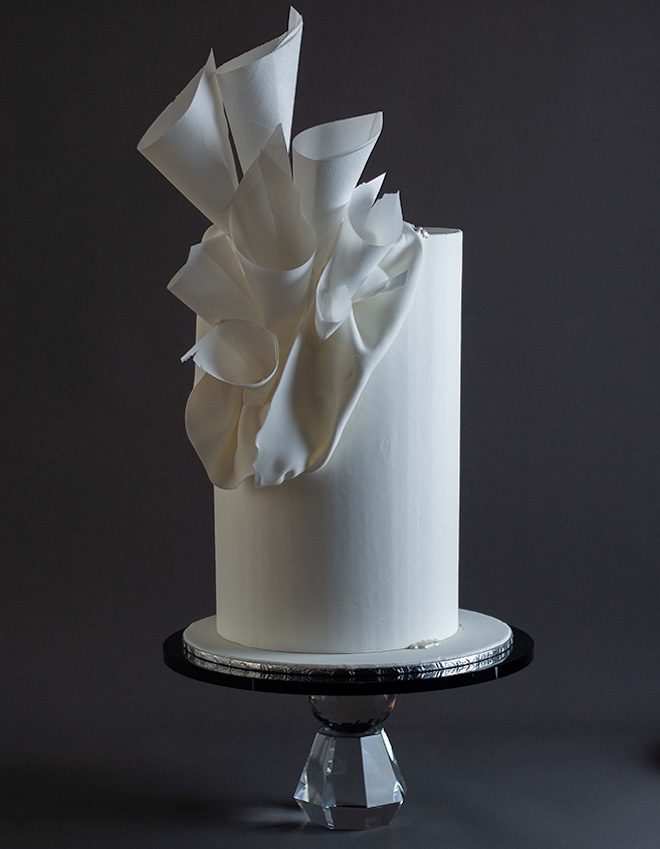 A white opulent wedding cake with unique embellishments.