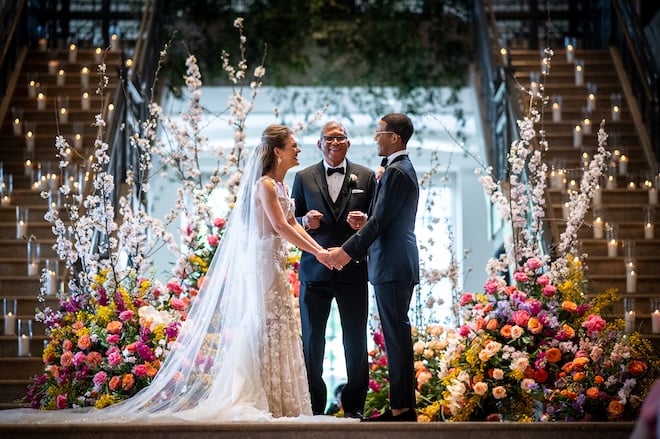 The bride and groom hold hands on the altar at their wedding ceremony at the Corinthian Houston.