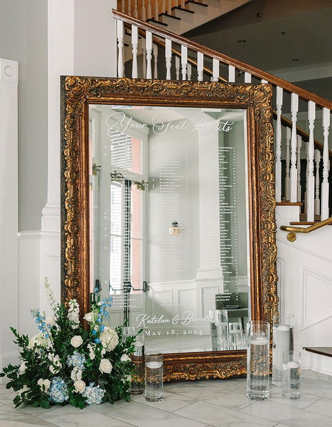 A mirrored seating chart for wedding guests to find their seats at the blue and white ballroom wedding.