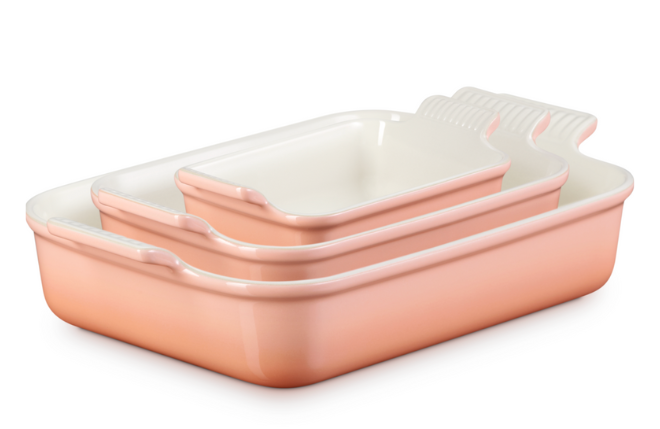 Three peach baking dishes in different sizes by Le Creuset.