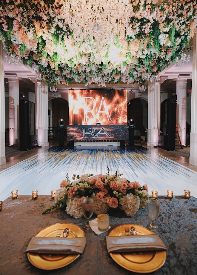 The sweetheart table overlooking the dance floor with a screen that has an "RA".