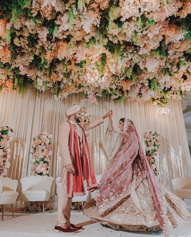 The bride and groom dancing under a floral canopy.