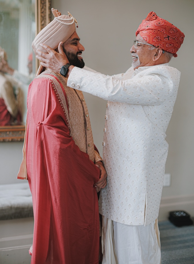 The groom's father holding the groom's face and smiling.