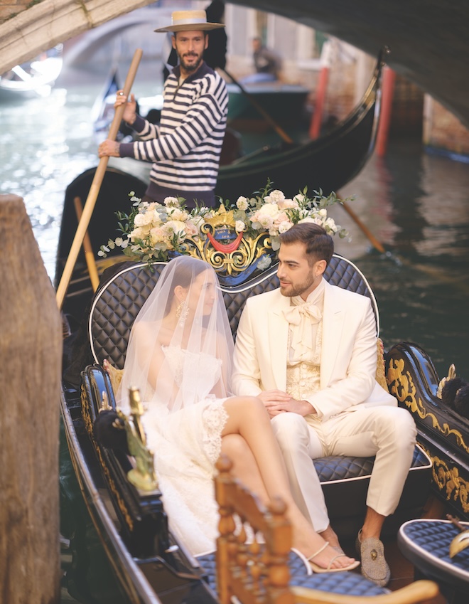 The bride and groom holding hands while in the gondola.