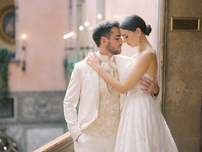 The bride and groom touching foreheads on a balcony.