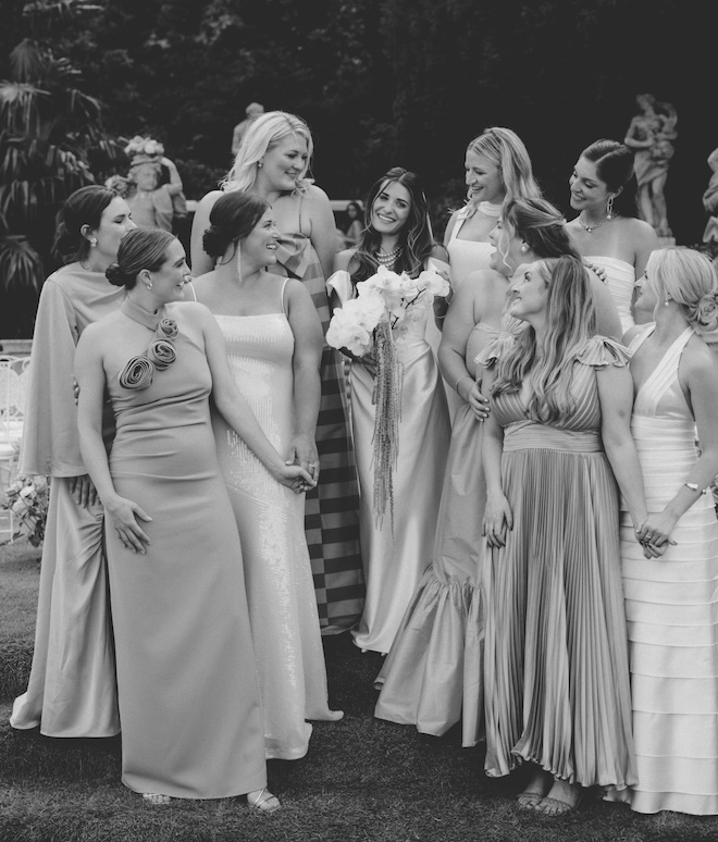 A bride smiling with her bridesmaids surrounding her.