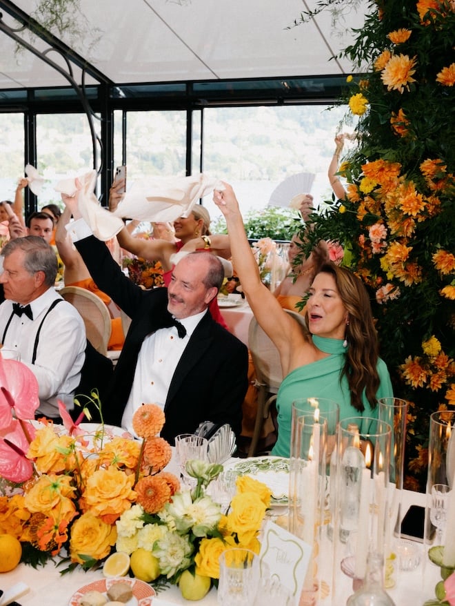 Guests waving their napkins in the air as they are seated at the reception tables.