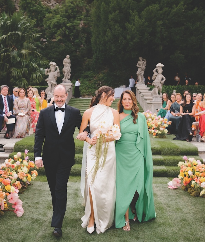 The bride walking down the aisle with both of her parents.