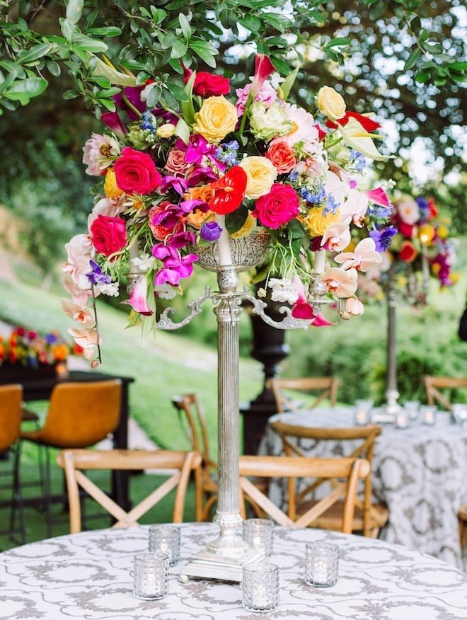 A floral centerpieces with yellow, pink, purple and red florals. 