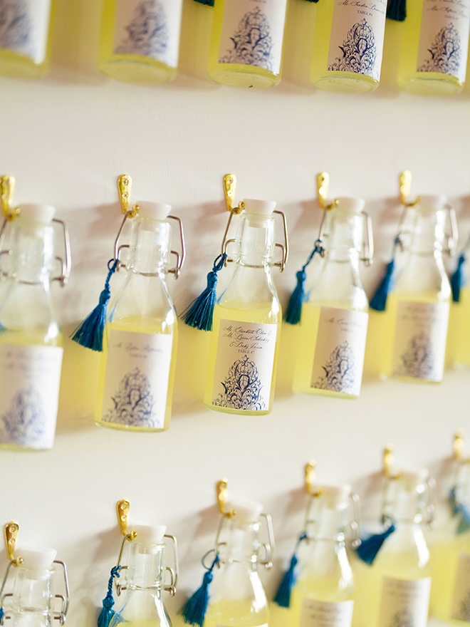 Mini bottles of limoncello are hung on a wall for wedding guests.