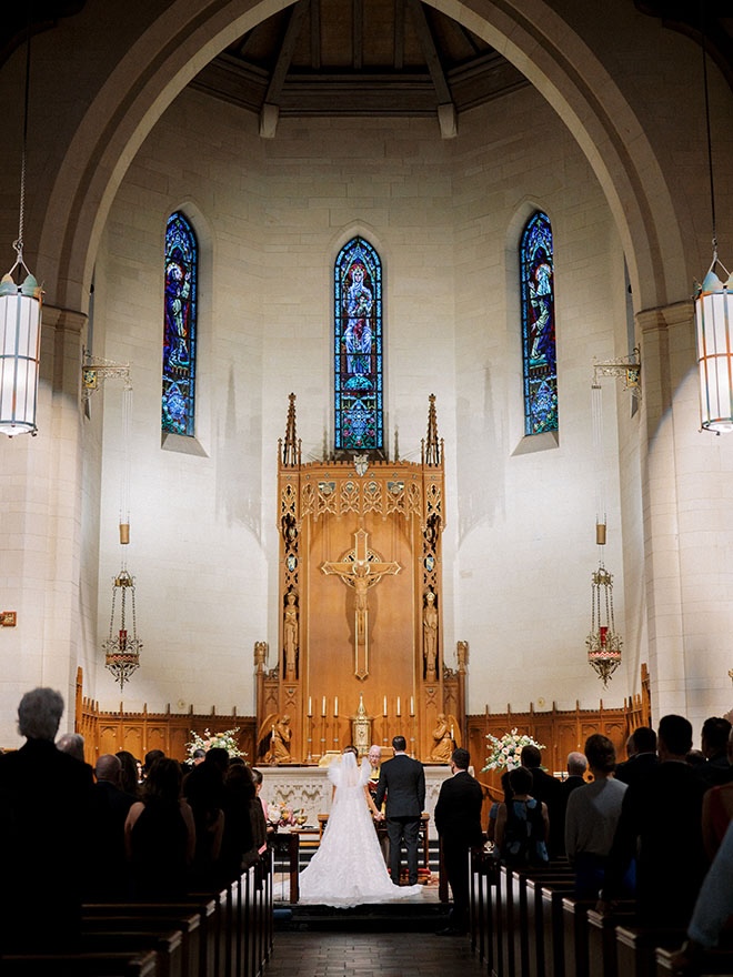 The bride and groom hold hands on the altar at their church ceremony.