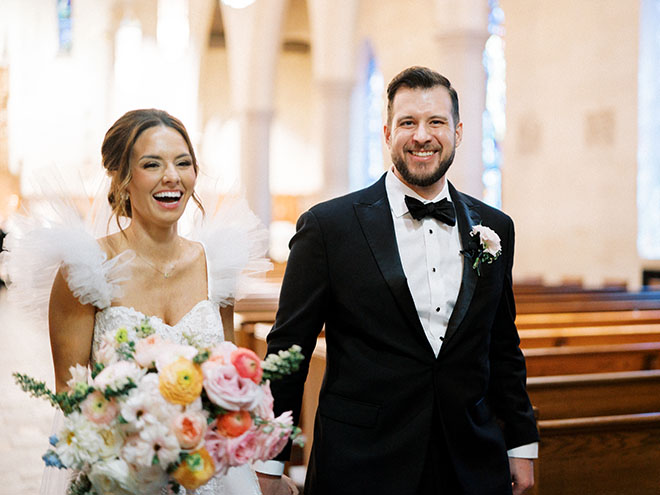The bride and groom walk down the aisle after their wedding ceremony smiling. 