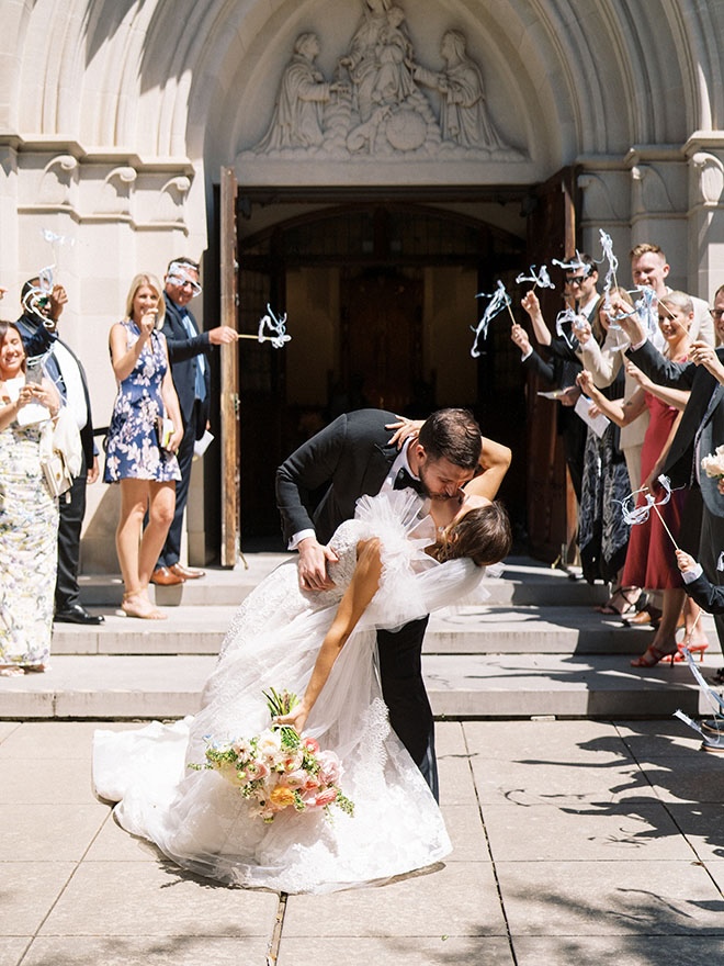 Wedding guests celebrate as the couple kiss outside the church.
