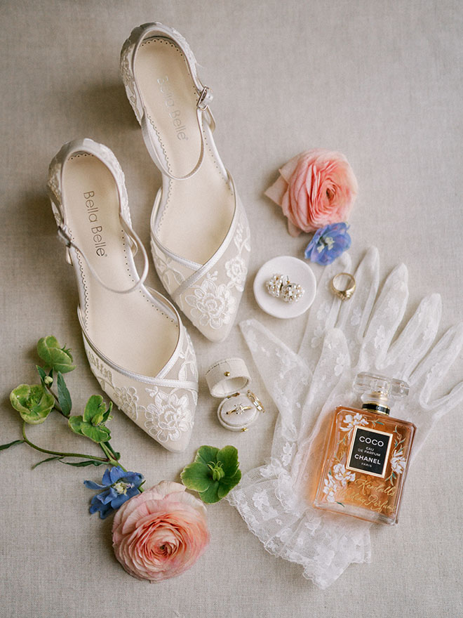 The bride's bridal accessories lay next to pink and blue flowers. 