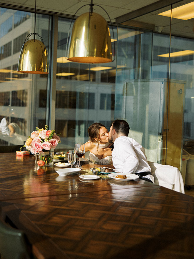 The bride and groom share a kiss during their private dinner at the Petroleum Club of Houston before their wedding reception. 
