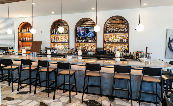 Masraff's Restaurant features a bar with built in wooden shelves and high top seating.