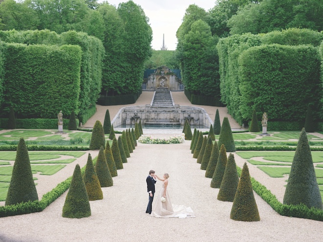 The groom kissing the bride's hand in the garden of the chateau.