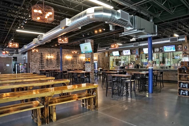 The interior of SpindleTap Brewery has exposed bricks, high top tables and picnic tables. 